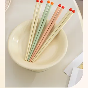 Close-up of colorful dopamine-style chopsticks with round ball tips in a cream bowl