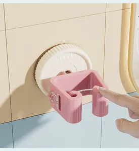 Pink suction cup mop holder wall-mounted on bathroom tiles with finger press detail