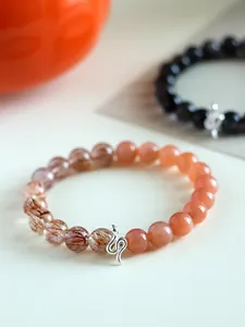 Detail view of 925 silver snake charm bracelet with sunstone and super seven beads