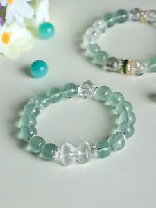 Close-up of a delicate green fluorite and white quartz beaded bracelet with a crystal bowknot.