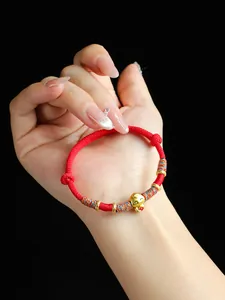 Vue macro détaillée d'un bracelet tissé rouge fait main avec un charme de serpent doré
