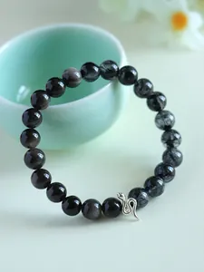 Detailed view of a 925 silver snake charm on a black crystal and sunstone beaded bracelet