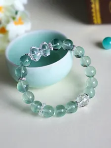 Close-up of elegant green fluorite and white crystal beaded bracelet featuring a bow charm