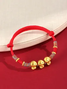 Détail du bracelet rouge tissé main avec breloques serpent dorées pour l'Année du Serpent