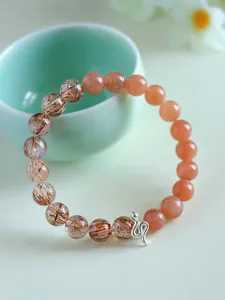 Detail of a 925 silver snake charm bracelet with sunstone and super seven crystal beads.