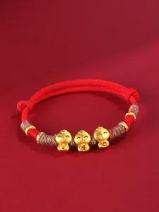 Gros plan de trois breloques serpent dorées sur un bracelet en cordon rouge tressé main