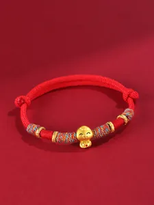 Détail d'un bracelet tressé rouge avec un pendentif serpent porte-bonheur en or