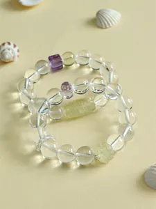 Nahaufnahme von eleganten Kristallarmbändern mit geschnitztem Lotus und gelber Dzi-Perle