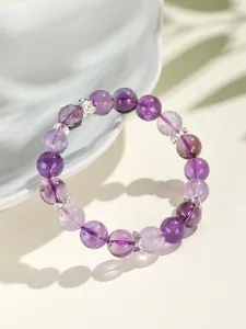 Gedetailleerde macro-opname van een amethist kralenarmband met zilveren vlinderbedels