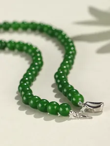 Primo piano dei grani di calcedonio verde da 8 mm e della chiusura in metallo lucido