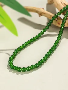 Dettaglio di una collana con perle di calcedonio verde da 8mm su sfondo di sabbia naturale