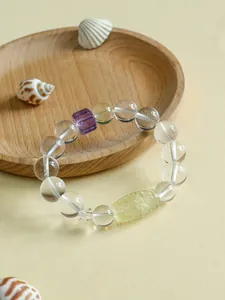 Detailansicht Kristallarmband mit Citrin-Dzi-Perle und Amethyst auf einem Holztablett.