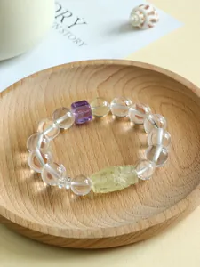 Nahaufnahme von Kristallarmband mit Citrin-Dzi-Perle und Amethyst auf Holztablett