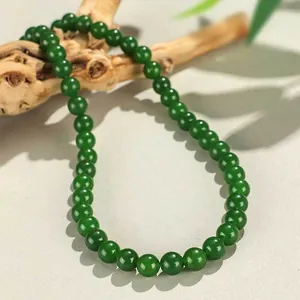 Elegante collana di perle tonde di calcedonio verde da 8mm posata su ramo di legno