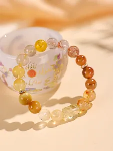 Primer plano de pulsera de cuarzo rutilado amarillo con dije de Pixiu de cristal tallado