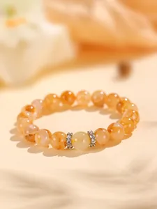 Detalle de una pulsera elegante de cuentas de cuarzo rutilado dorado y cristales