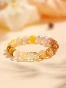 Vista detallada de una pulsera de cuarzo rutilado amarillo con un dije de PiXiu tallado.