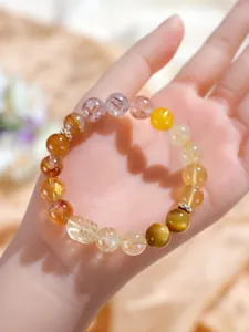 Detalle de pulsera de cristal multitesoro con cuarzo rutilado dorado y cuenta de Pixiu.