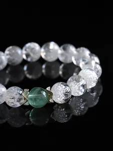 Dettaglio macro del bracciale in cristallo con gemma verde e cappucci in argento a fiore