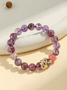 Close-up detail of purple amethyst beads and a golden snake charm on this fashion bracelet.