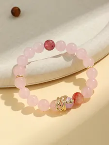 Close-up detail of a rose quartz beaded bracelet featuring a crafted golden snake charm