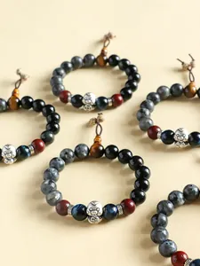 Detailed view of 999 silver snake charm on black agate and tiger eye bracelets