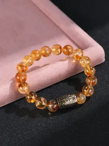 Detalle macro de una pulsera de cuentas de cristal amarillo con una pieza de metal antiguo