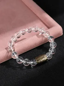 Detalle macro de pulsera de cuentas de cristal transparente con un dije de oro vintage