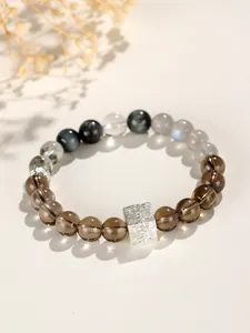 Nahaufnahme eines natürlichen Edelstein-Armbands mit Rauchquarz und silbernem Anhänger.