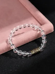 Detalle macro de pulsera de cuentas de cristal transparente con una cuenta de metal dorado
