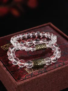 Detalle de pulsera de cuentas de cristal transparente con cuenta de metal dorado antiguo.