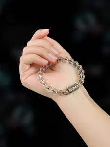 Detalle de la pulsera de cuentas de cristal super seven de oro negro de 8-10 mm en la mano
