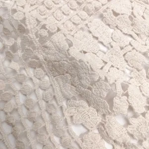 Close-up detail of white 3D hollow cotton lace embroidery with floral patterns