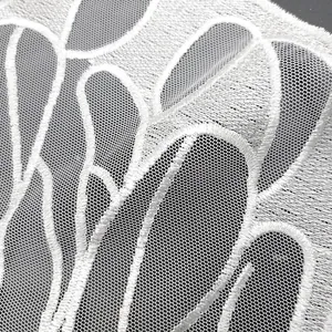 Detail view of intricate white butterfly wing lace embroidery on fine mesh fabric base