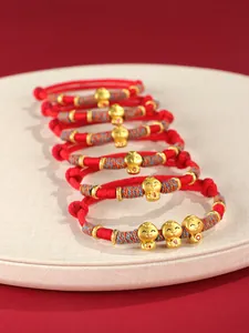 Vue détaillée de bracelets tressés rouges avec breloques serpent dorées pour l'année du serpent