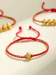 Dettaglio di bracciale intrecciato rosso con ciondolo a forma di serpente dorato portafortuna