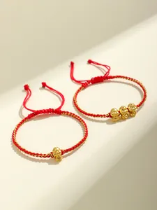 Vista dettagliata di braccialetti intrecciati rossi fatti a mano con ciondoli a forma di serpente dorato