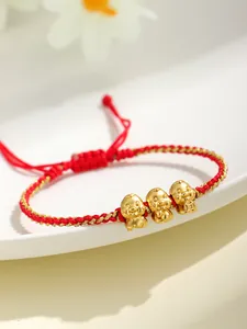 Dettaglio di un bracciale rosso intrecciato con tre ciondoli portafortuna a serpente.