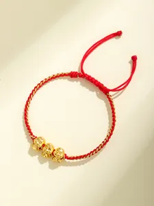 Dettaglio del braccialetto in corda intrecciata rossa con tre piccoli ciondoli serpente