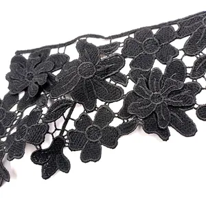 Detailopname van zwart wateroplosbaar kant met 3D geborduurde bloemen en bladmotieven