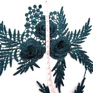 Detailed view of 3D emerald green floral lace appliqué shown with measuring tape