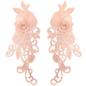 Detailed view of a pair of symmetrical 3D floral lace appliques in soft peach pink.