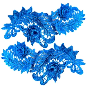 Nahaufnahme von symmetrischen 3D-Blumenstickerei-Spitzenaufnähern in Blau auf weißem Grund
