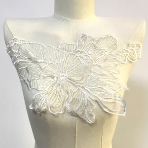 Gros plan sur une applique en dentelle blanche à paillettes avec broderie florale