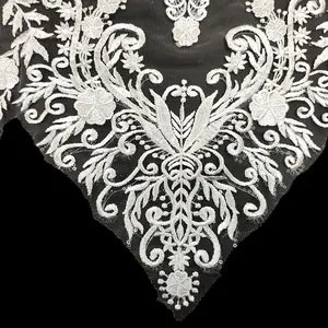 Dettaglio di ricamo in pizzo bianco con paillettes su rete nera per abiti da sposa
