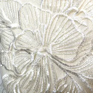 Détail en gros plan d'un écusson brodé floral blanc à paillettes sur dentelle mesh