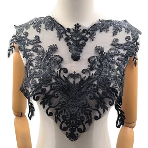 Dettaglio di un'applique in pizzo nero ricamato con paillettes e trama floreale fine