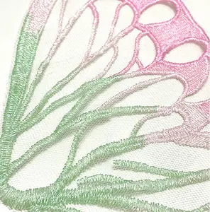 Macro view of mint green and pink butterfly lace embroidery patch for DIY crafts