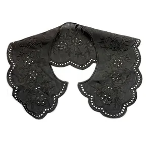 Macro view of black embroidered hollow lace detachable collar with scalloped edges.