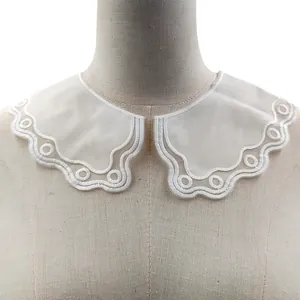 Close-up of white embroidered detachable doll collar with scalloped edges and lace detail